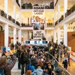 Protestors unfurl a banner in reference to the Indian conglomerate Adani at the Science Museum in London on March 23, 2024.