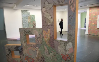 A person seen walking through a gallery amid wallpaper-like elements.