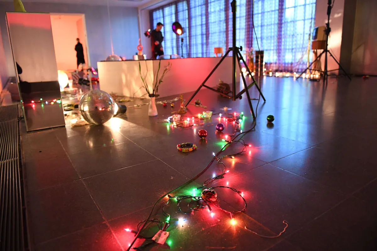 A lighting structure set atop a string of pink and green lights. A disco ball can be seen on the floor nearby.