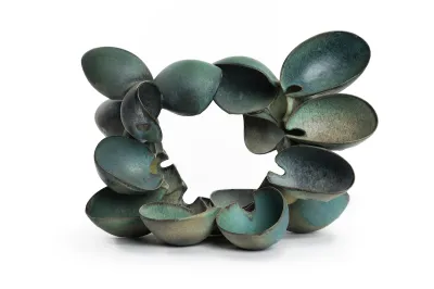 A group of bowl-like blue ceramic forms pinched together to form a U shape.