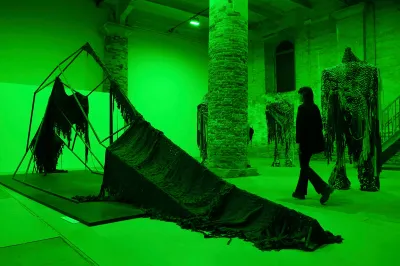 A person walking near a sculpture in a green-tinted room.