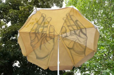 A parasol with hand drawn on them is open in a forest. 