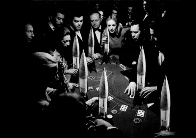 A photocollage of people standing around a casino table that is lined with warheads.