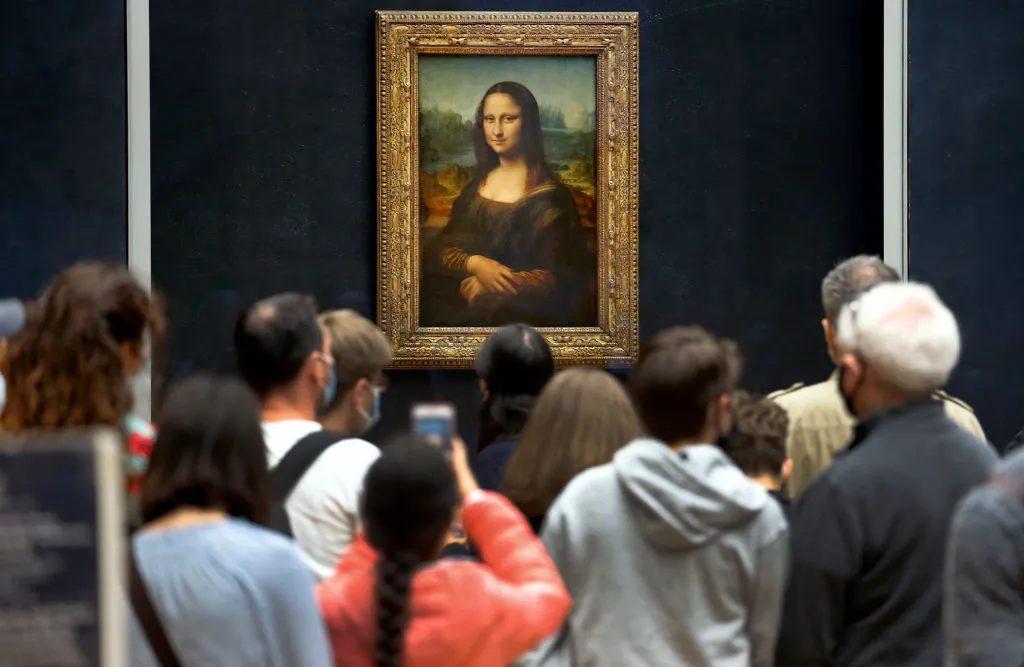 PARIS, FRANCE - JULY 06: Visitors wearing protective face masks queue to see the painting of 