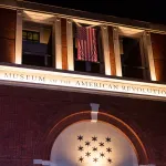 A museum facade with an American flag hanging above the words 