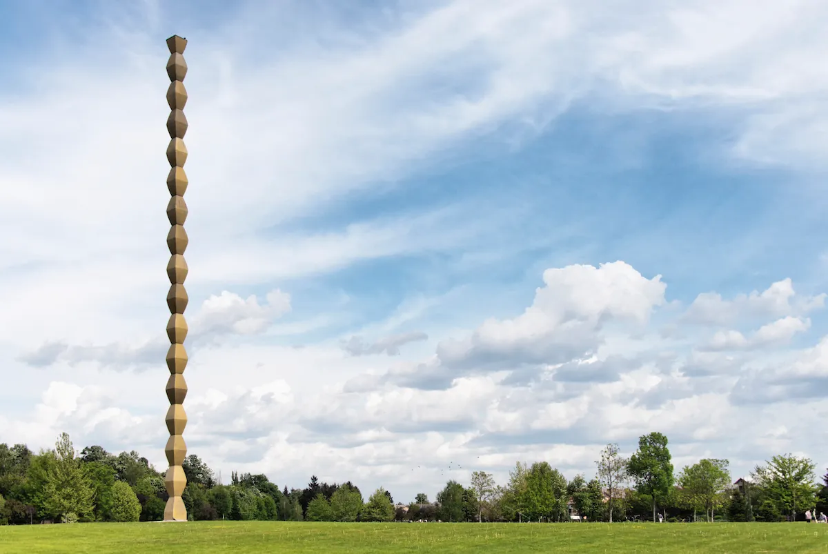 A tall column formed from repeating cast-iron modules in a park.