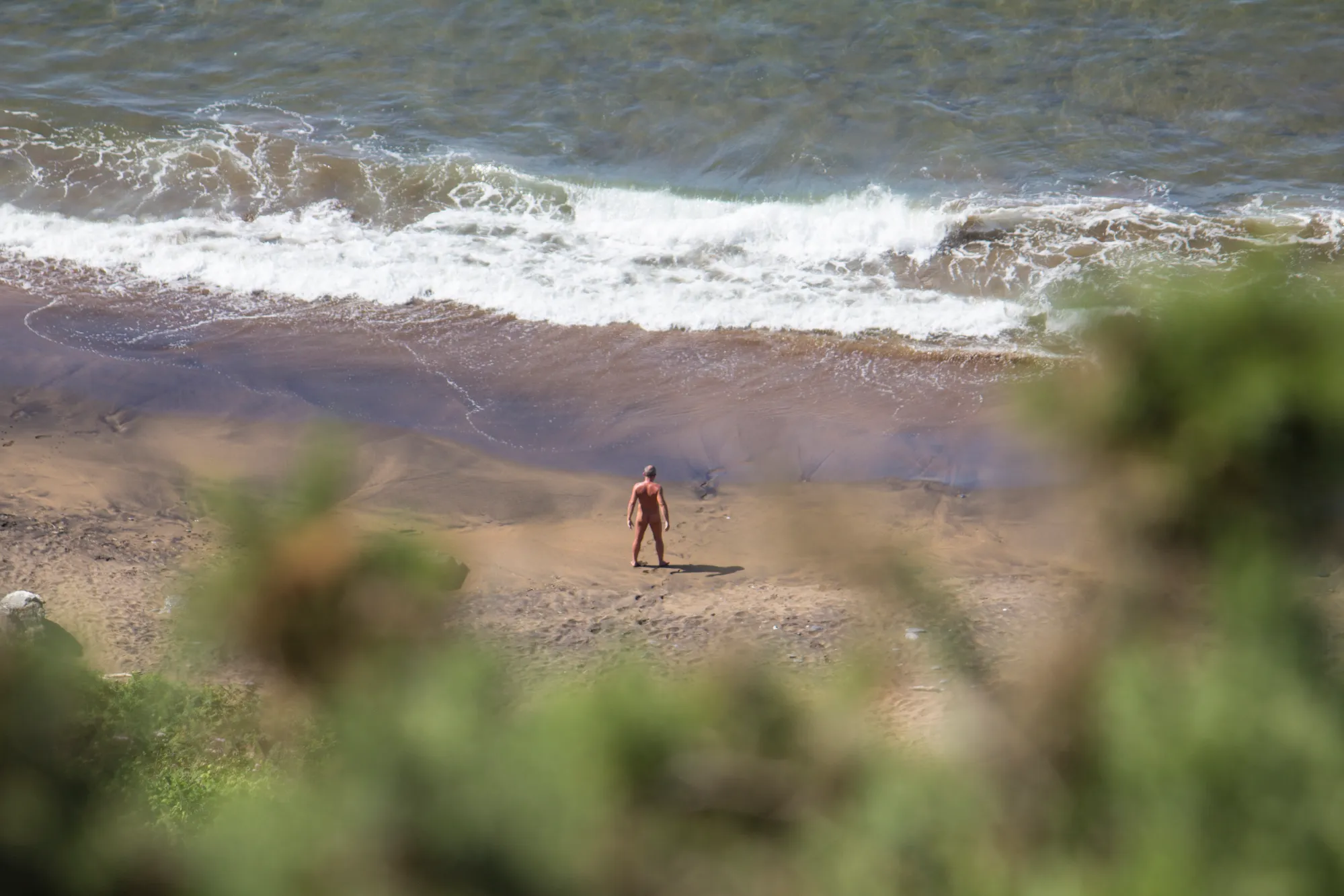 A naked man on a beach.