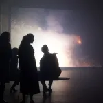 Four people watch a screen showing fireworks.