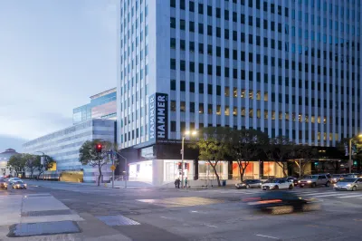 Exterior of the Hammer Museum as cars drive by a busy intersection. 