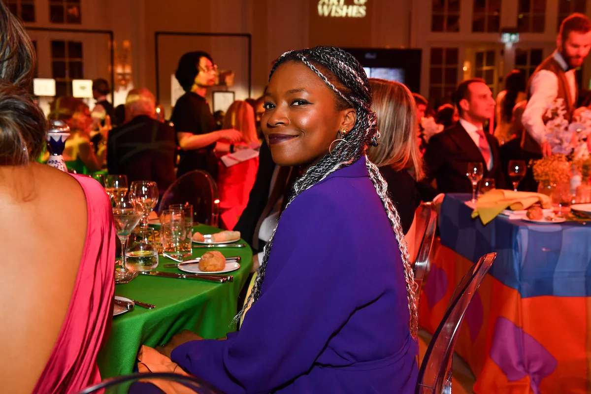 A smiling Black woman in a purple dress at a gala.