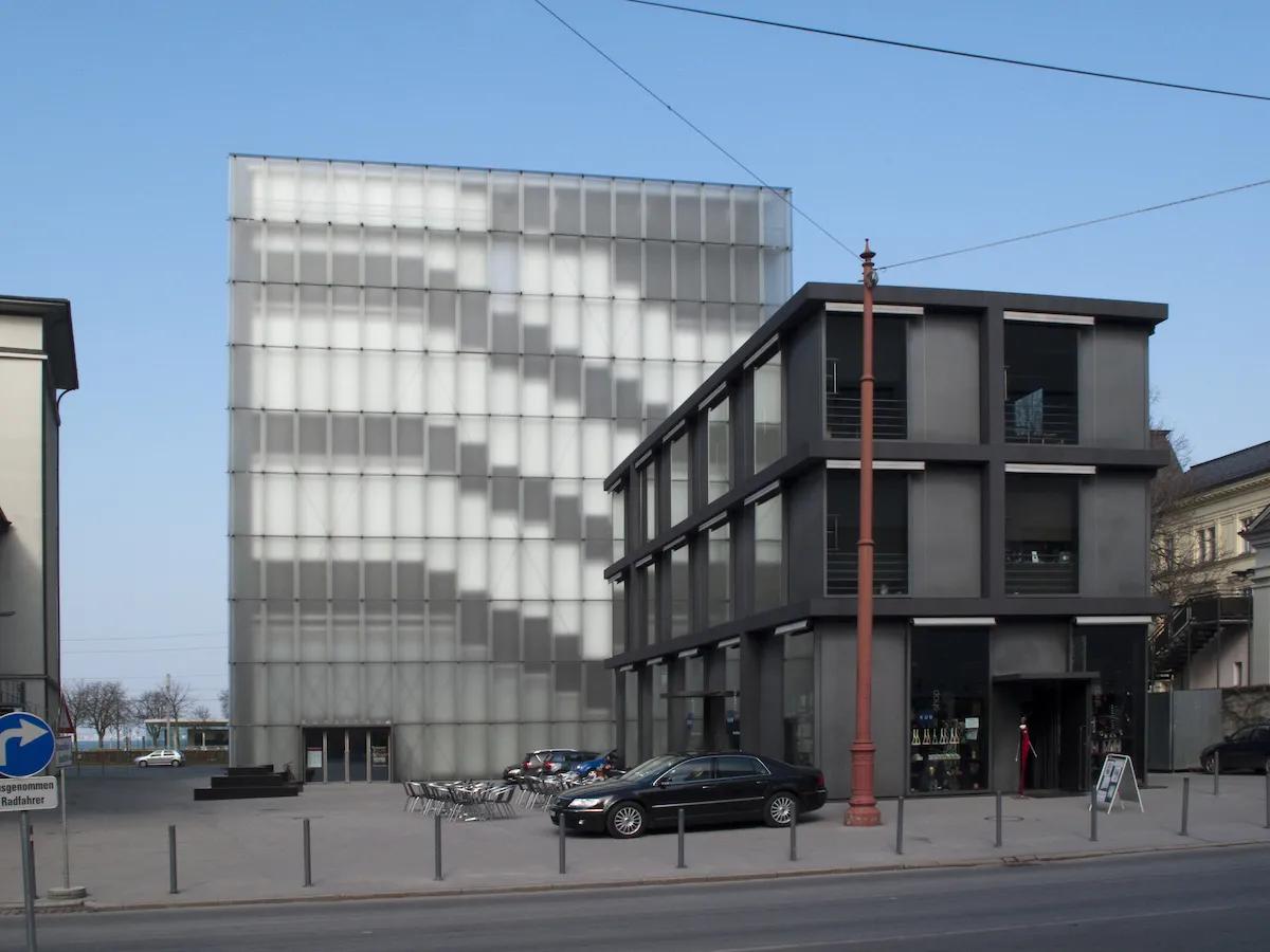 A spare museum building with cars parked outside it.