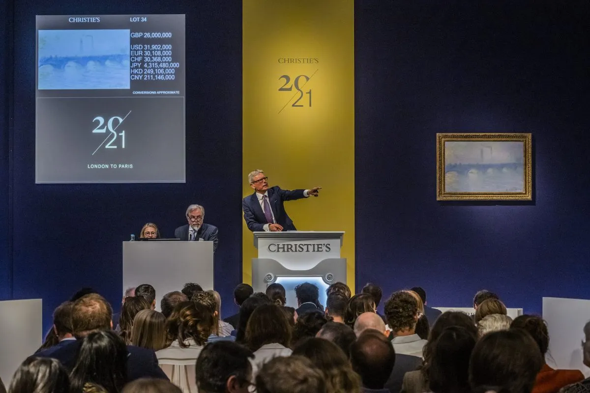 A man stands on a rostrum at an auction.