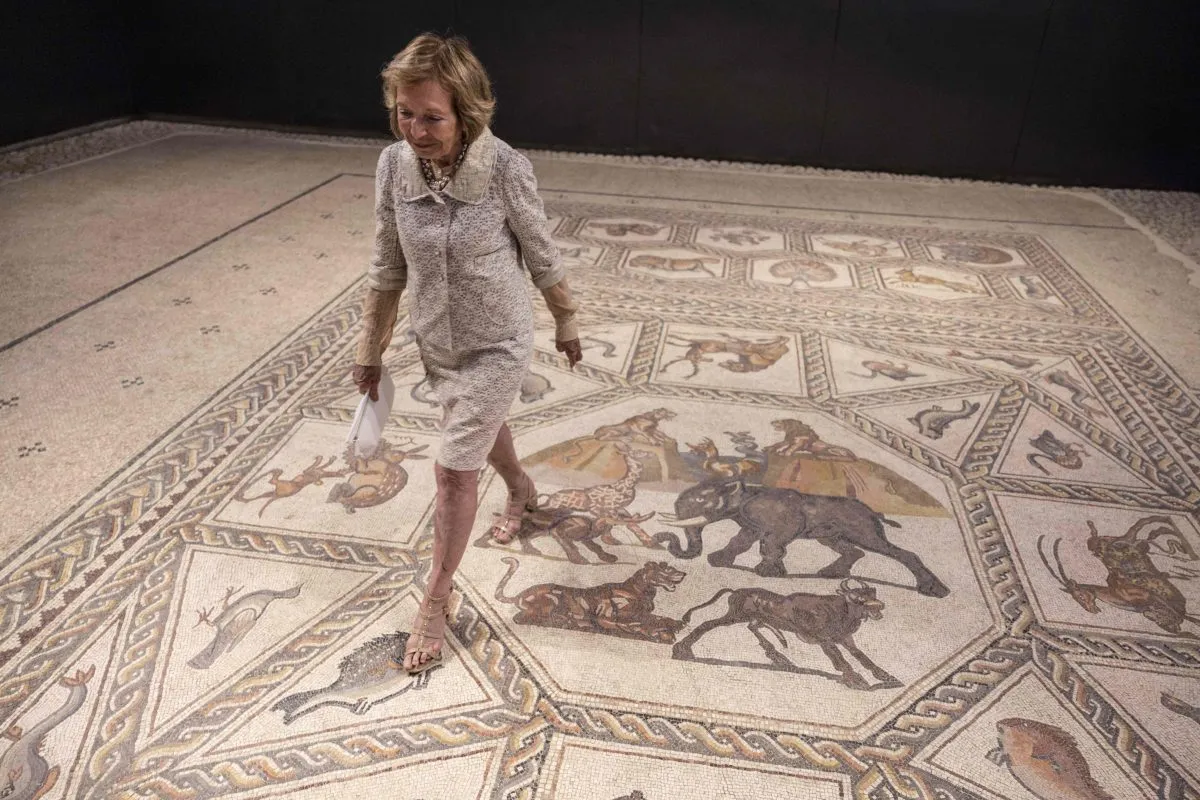 US philantropist Shelby White poses for a picture on the roughly 1,700-year-old Lod mosaic, ahead of the inauguration of a new visitors centre she helped fund to display the prized piece in the mixed city of Lod in the centre of Israel, on June 27, 2022. - The Lod Mosaic Archaeological Center was specifically built to house the Roman mosaic dating back to the 3rd or 4th century CE, which was unearthed in the city in 1996 and described as 