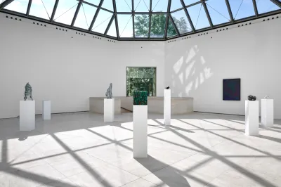 A group of plinths beneath a windowed ceiling.