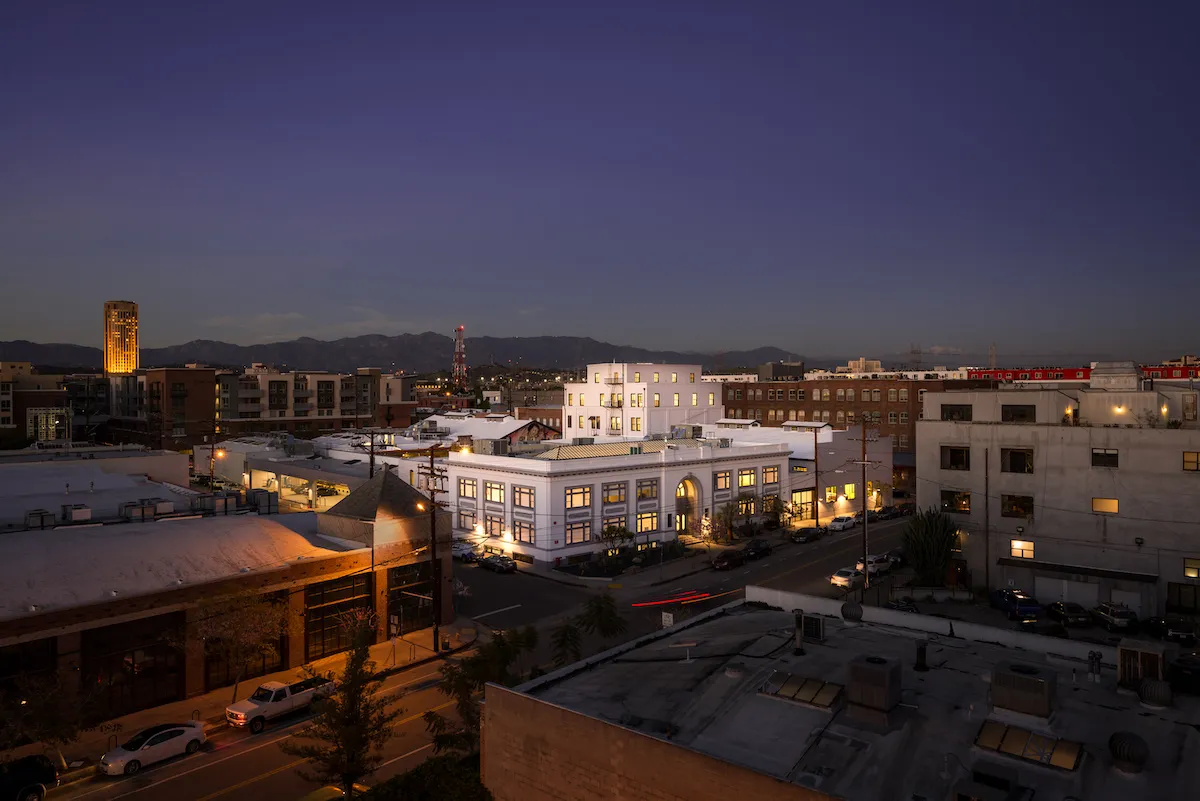 A gallery lit up at night amid other buildings.