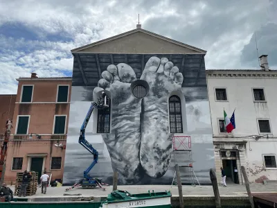 A grayscale mural of supine feet seen from the bottom, covering the facade of a prison.