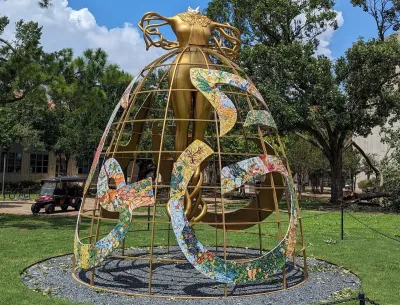 A sculpture of a female figure with branch-like arms wearing a hoop skirt. The figure