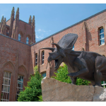 An old building with spires and a dinosaur.