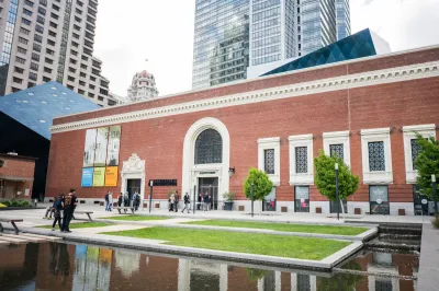 A museum building with a grassy courtyard and a reflecting pool in front of it.