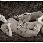 Photographer Sally Mann relaxes with her dog Honey in a meadow of tall grass on her farm near Lexington, Virginia.