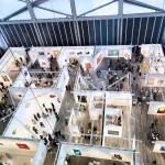 An aerial view of an art fair showing about a dozen booths with several people walking in it.