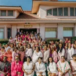 Women dressed in shades of pink stand outside the Alpha Gamma Omega House in Los Angeles.